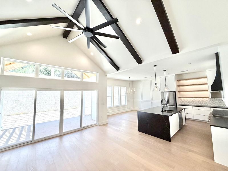 Kitchen with open shelves, a center island with sink, modern cabinets, white cabinetry, and hanging lights Kitchen with open shelves, a center island with sink, modern cabinets, white cabinetry, and hanging lights