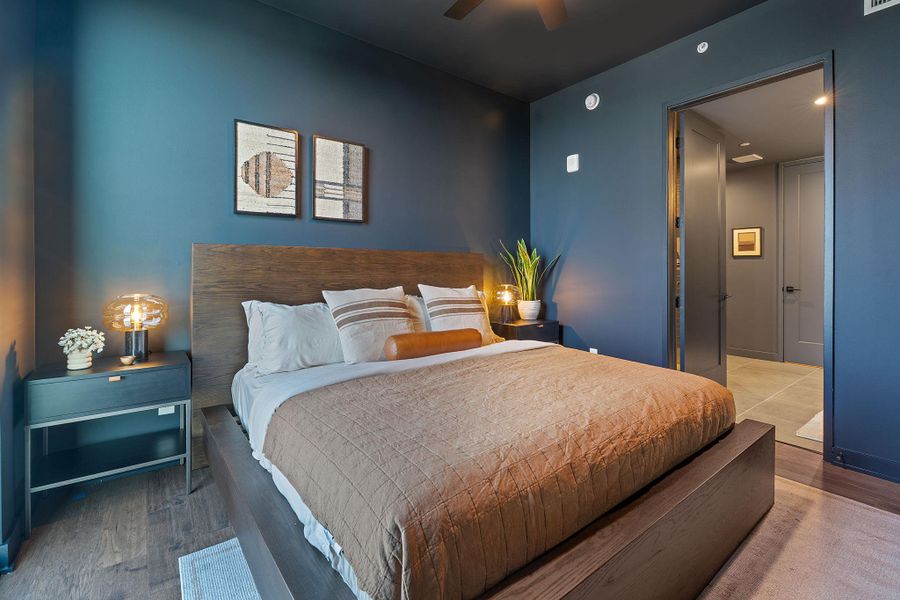 Representative Photo. Primary Bedroom with wood flooring, large window, ceiling fan, and window treatments included