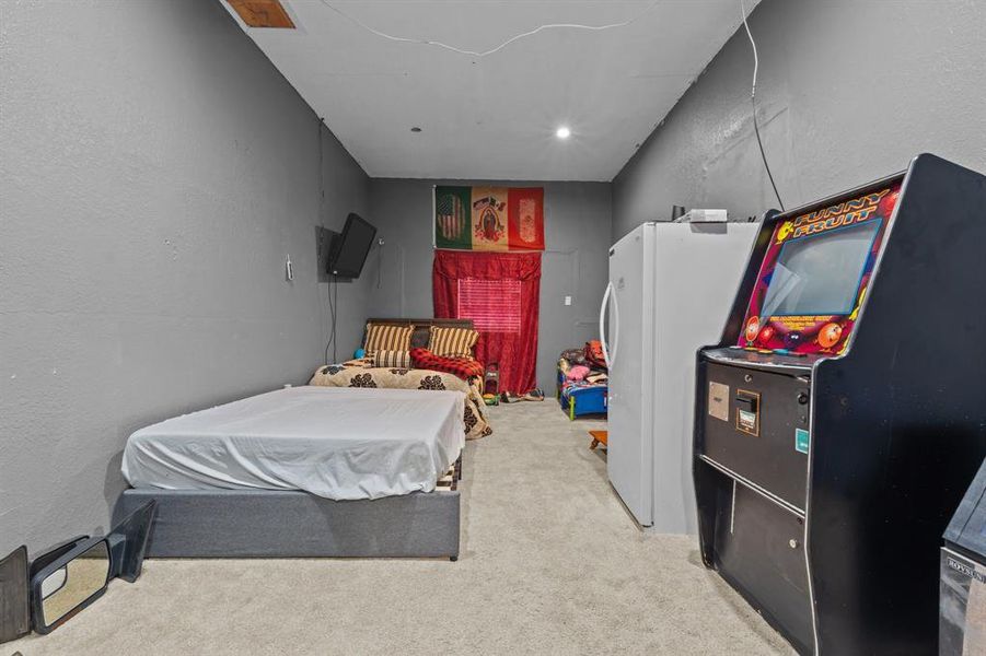 Bedroom featuring light colored carpet and white refrigerator