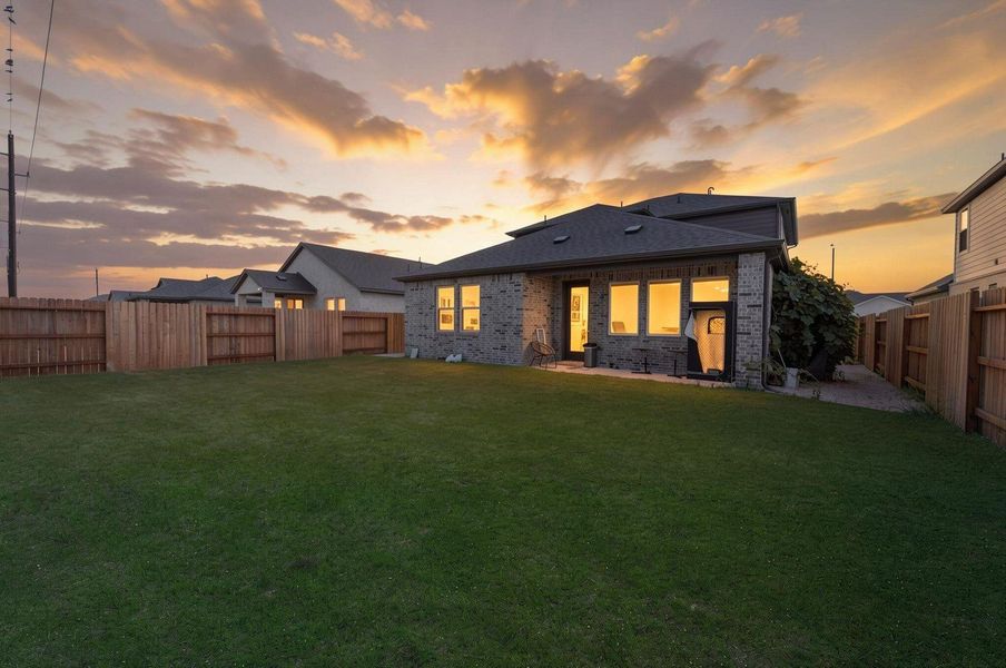The backyard opens to green space with no direct rear neighbors, giving the covered patio and lawn a more open backdrop. The evening view highlights the privacy and outdoor appeal of the lot. Virtually enhanced. The backyard opens to green space with no direct rear neighbors, giving the covered patio and lawn a more open backdrop. The evening view highlights the privacy and outdoor appeal of the lot. Virtually enhanced.
