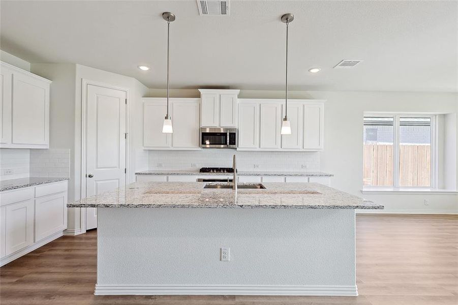 Kitchen featuring a kitchen island with sink and pendant lighting