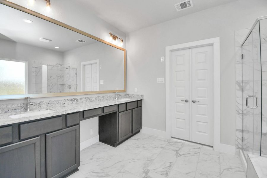 Elevate your daily routine at the elegant vanity, now equipped with double sinks, light countertops, modern hardware, and beautiful recessed lights. Sample photo of completed home with similar floor plan. Actual colors and selections may vary.
