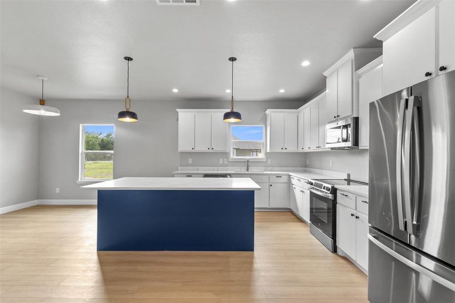 Kitchen featuring stainless steel appliances, a kitchen island, hanging light fixtures, recessed lighting, and white cabinets