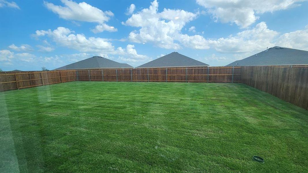 Spacious backyard featuring a full perimeter wood fence, expansive green lawn, and open sky Spacious backyard featuring a full perimeter wood fence, expansive green lawn, and open sky