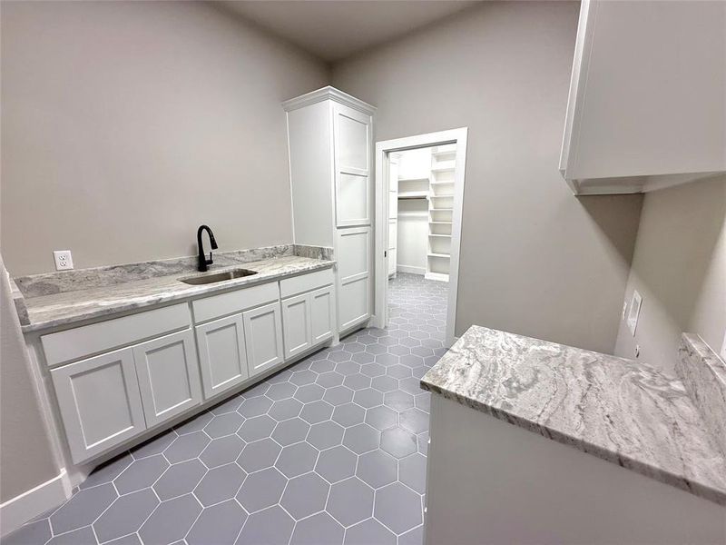 Kitchen featuring white cabinetry and light stone counters Kitchen featuring white cabinetry and light stone counters