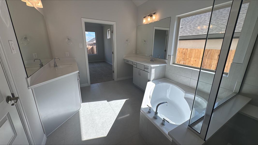Full bathroom featuring a garden tub, two vanities, and light tile patterned floors Full bathroom featuring a garden tub, two vanities, and light tile patterned floors