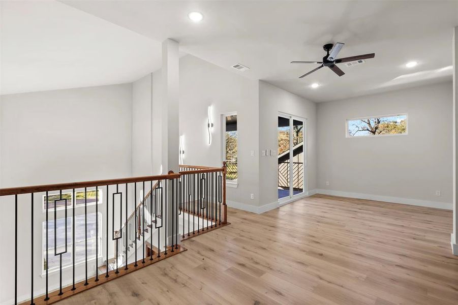 Spare room featuring ceiling fan, lofted ceiling, and light wood-type flooring