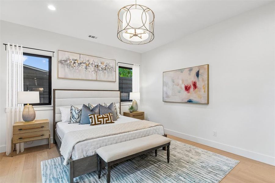 Spacious primary suite with designer lighting, warm wood floors, and serene views of the backyard.