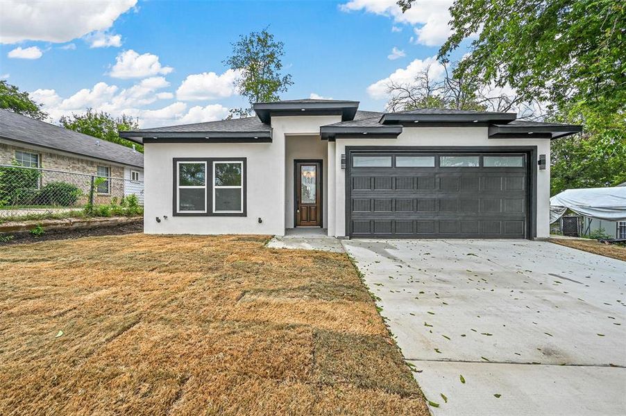 Prairie-style home featuring a garage and a front lawn