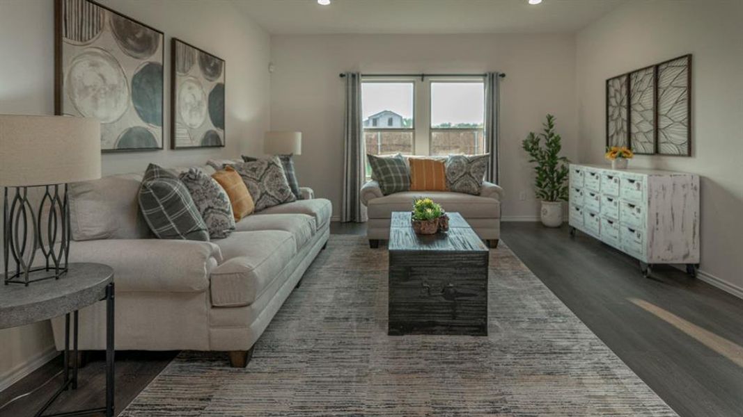 Spacious living area featuring dark wood-finish flooring, recessed lighting, and a large window providing natural light