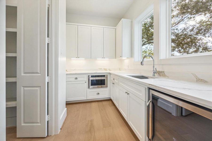 A walk-in pantry with custom cabinetry, a built-in microwave, and organized spaces for everything you can imagine. It reflects a sleek, functional layout that maximizes storage while maintaining a clean, modern look. Photo as of 11/5/2024