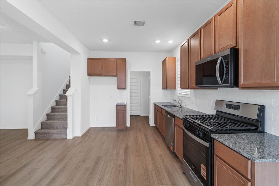 Additional view of the kitchen highlighting the granite countertops and backsplash.