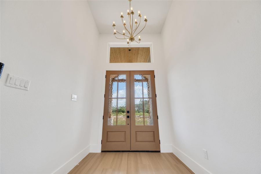 Beautiful double front doors with textured glass, a transom window, and an eye-catching modern light fixture. Beautiful double front doors with textured glass, a transom window, and an eye-catching modern light fixture.