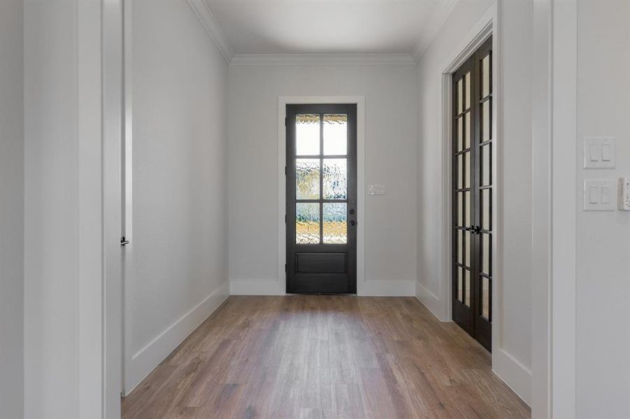 Doorway to outside featuring vinyl wood, crown molding