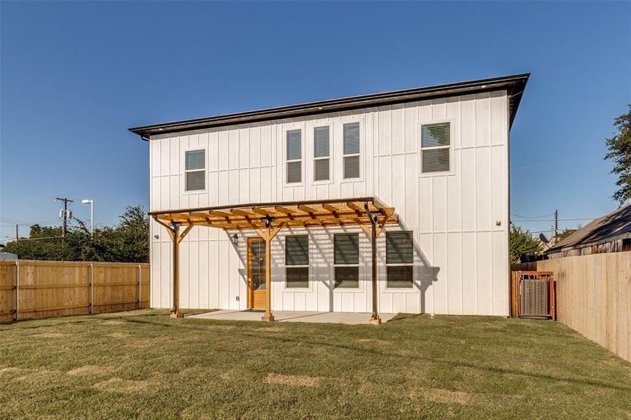 Rear view of property featuring a pergola, a fenced backyard, a patio, and board and batten siding Rear view of property featuring a pergola, a fenced backyard, a patio, and board and batten siding