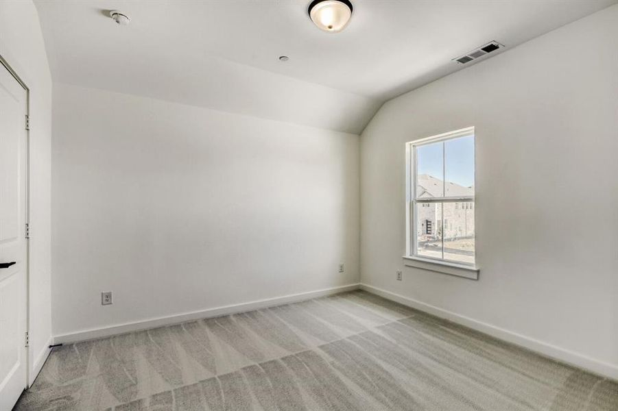 Unfurnished bedroom featuring vaulted ceiling and light colored carpet