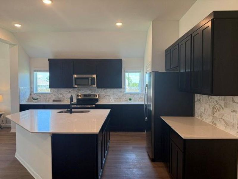 Kitchen featuring dark cabinetry, light countertops, and a patterned backsplash