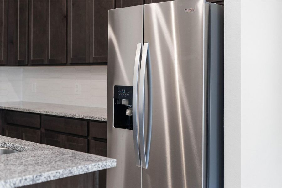 Kitchen comes equipped with a side-by-side Whirlpool refrigerator.