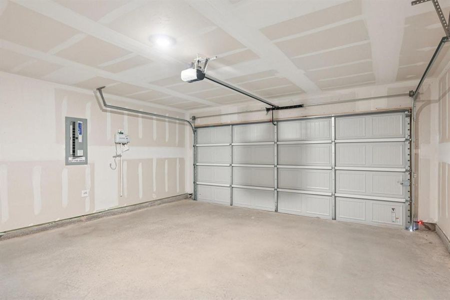 Spacious garage featuring a concrete floor, an overhead garage door opener, and a panel-style garage door Spacious garage featuring a concrete floor, an overhead garage door opener, and a panel-style garage door