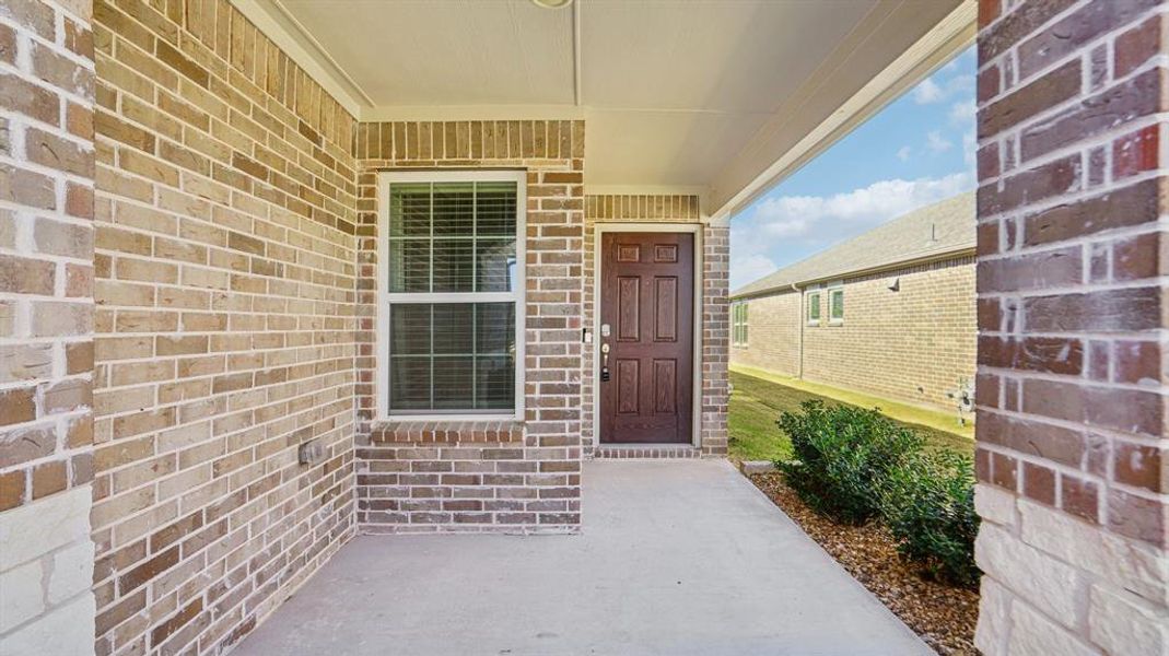 Entrance to property featuring a porch and brick siding Entrance to property featuring a porch and brick siding