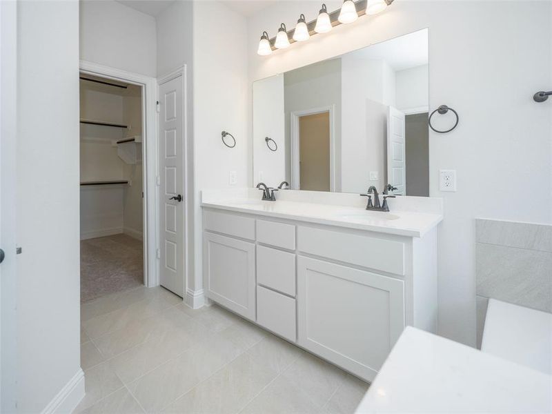Full bath with double vanity, light tile patterned flooring, and a spacious closet Full bath with double vanity, light tile patterned flooring, and a spacious closet
