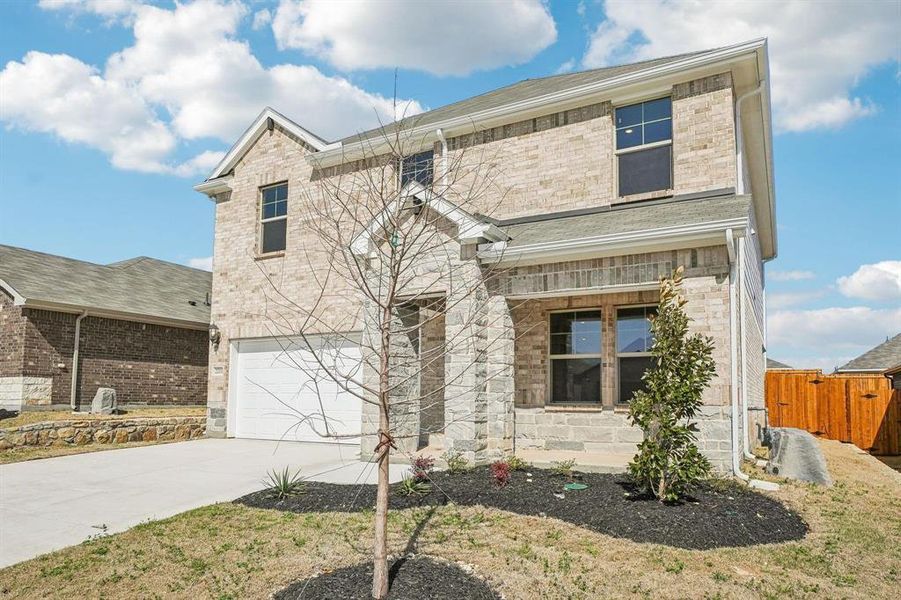 View of front facade featuring an attached garage, driveway, stone siding, and a porch View of front facade featuring an attached garage, driveway, stone siding, and a porch