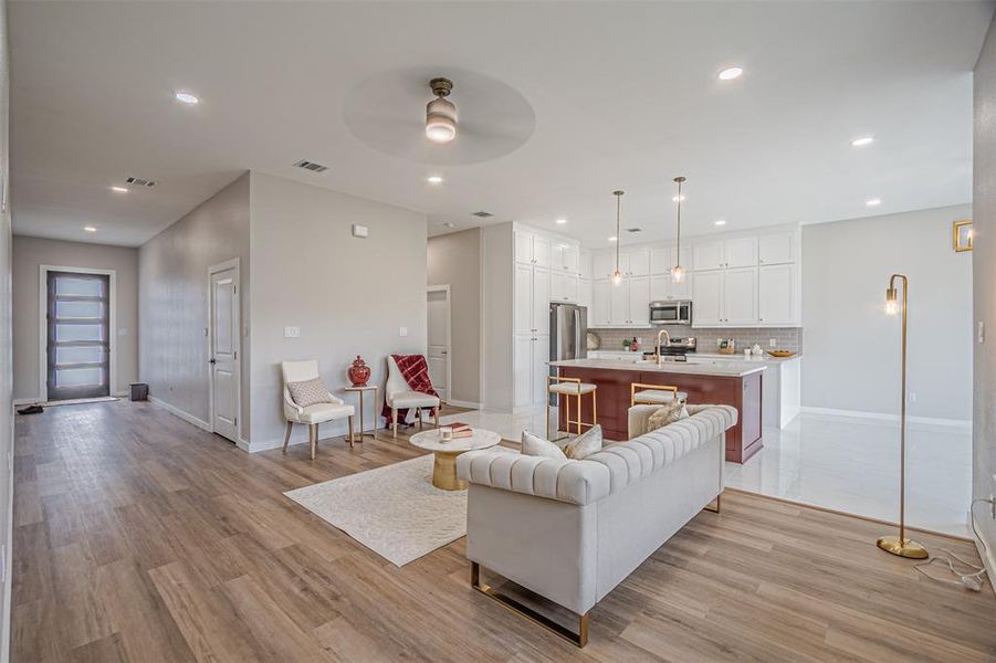 Living area with light wood-style flooring, ceiling fan, and recessed lighting