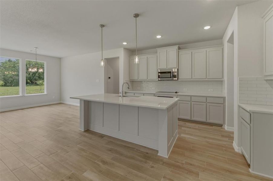 Kitchen with a central island featuring a stainless steel sink, white countertops, and pendant lighting
