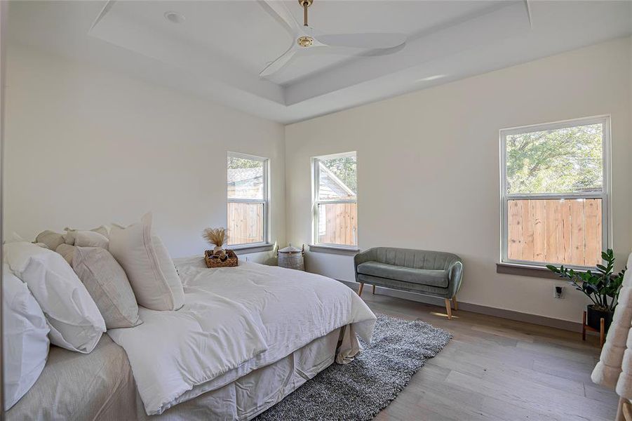 Bedroom featuring a tray ceiling, wood finished floors, and a ceiling fan