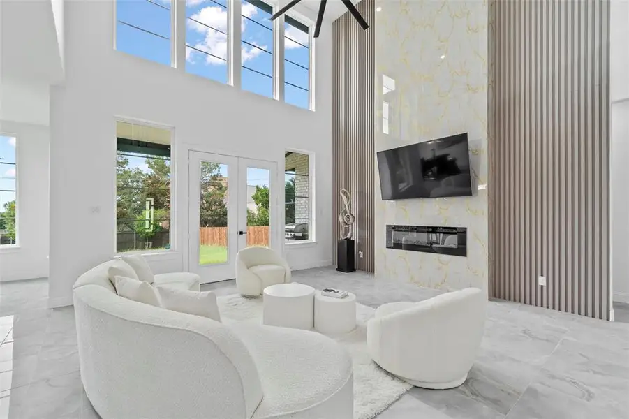Spacious living area featuring a double-height ceiling, large format tile flooring, and multiple windows
