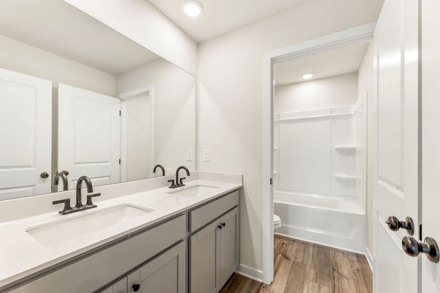 A bathroom with a tub sink and a mirror. A bathroom with a tub sink and a mirror.