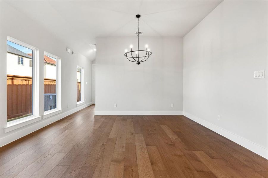 Unfurnished dining area with hardwood / wood-style flooring, a notable chandelier, and lofted ceiling