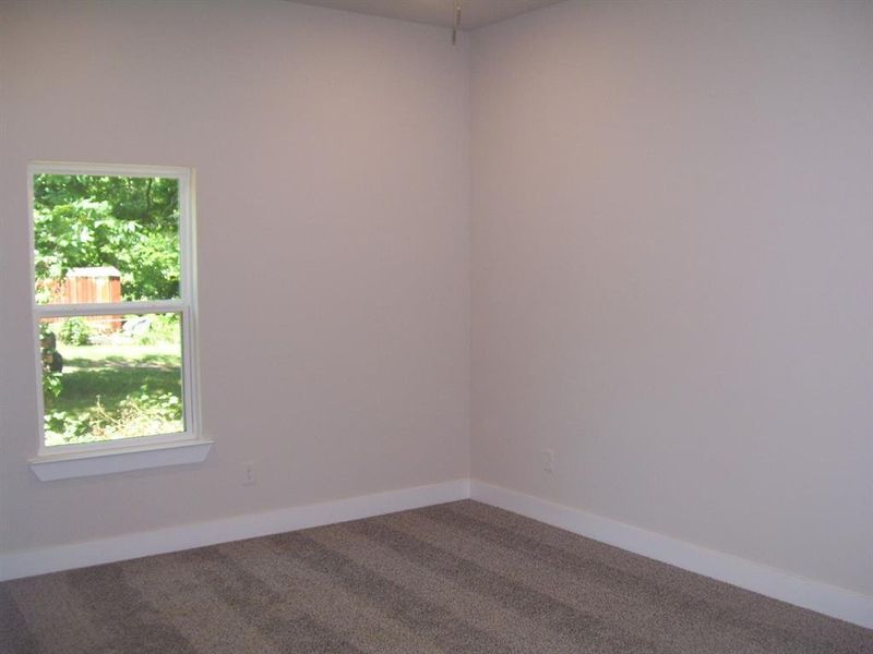 Empty room featuring dark colored carpet and baseboards Empty room featuring dark colored carpet and baseboards