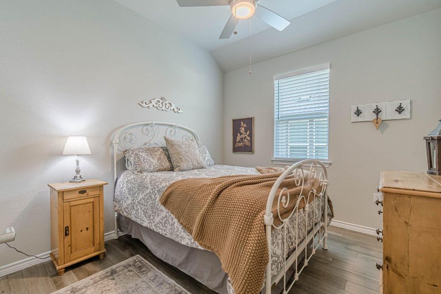 Bedroom with vaulted ceiling, baseboards, wood finished floors, and a ceiling fan
