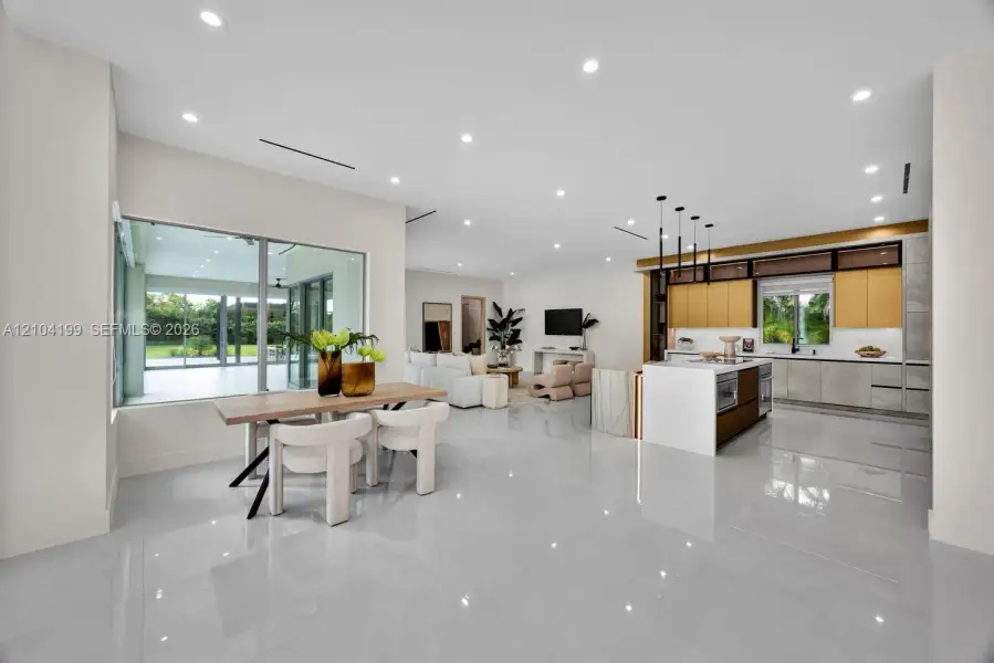 Open-concept interior featuring large-format tile flooring, recessed lighting, and a kitchen equipped with a central island and contemporary flat-panel cabinetry