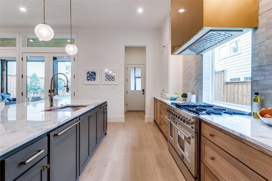 Kitchen with a sink, pendant lighting, light wood finished floors, range with two ovens, and baseboards Kitchen with a sink, pendant lighting, light wood finished floors, range with two ovens, and baseboards