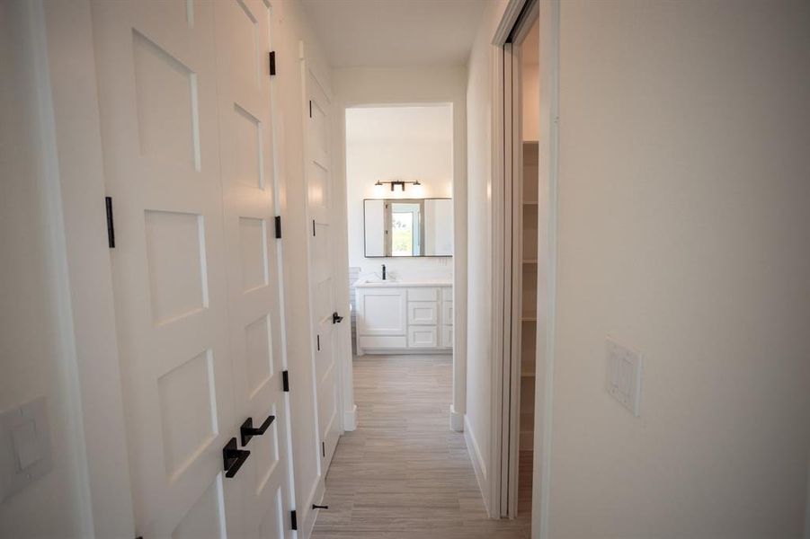 Hallway with light wood-style flooring and a sink Hallway with light wood-style flooring and a sink