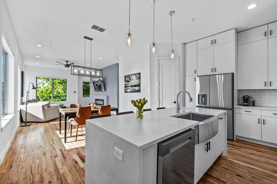 Kitchen featuring white cabinets, a kitchen island, appliances with stainless steel finishes, and light wood flooring