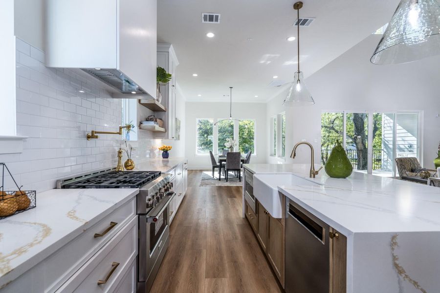 Pro-style gas range, built-in dishwasher, and sleek lighting over the waterfall island. Pro-style gas range, built-in dishwasher, and sleek lighting over the waterfall island.