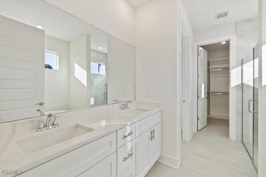 Full bath with a marble finish shower, double vanity, and a spacious closet Full bath with a marble finish shower, double vanity, and a spacious closet
