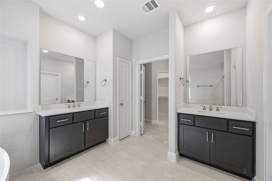 Spa-like Splendor: Dual vanities, a roomy linen closet, and a secluded water closet are set amid abundant space for an everyday spa experience right at home.