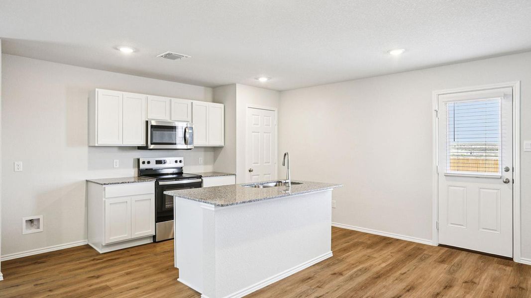 Kitchen featuring wood-finish flooring, white cabinetry, granite countertops, a stainless steel microwave, and a stainless steel oven/range