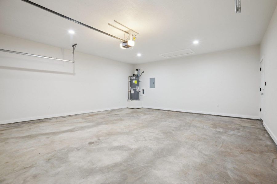 Garage featuring secured water heater, electric panel, and recessed lighting