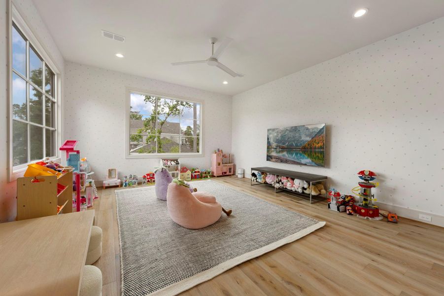 Spacious upstairs game room filled with natural light, featuring wood flooring, large windows, and plenty of room for play, media, or a flexible family gathering space.