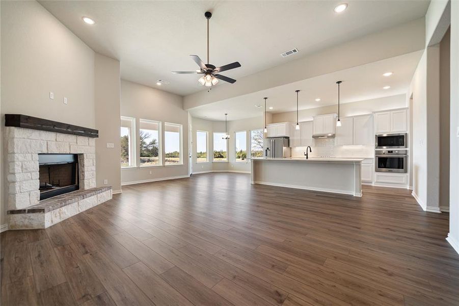 Unfurnished living room with a fireplace, a ceiling fan, dark wood-type flooring, and recessed lighting