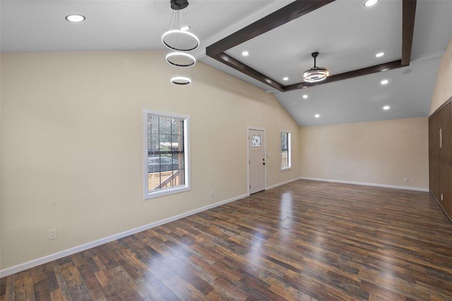 Unfurnished living room featuring beam ceiling, a healthy amount of sunlight, wood-type flooring, and high vaulted ceiling