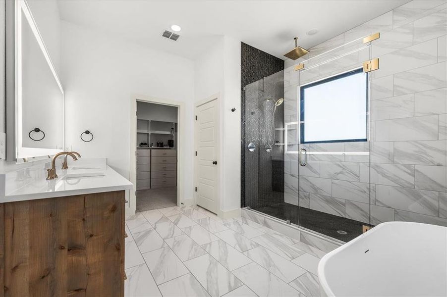 Ensuite primary bath features marble tile floors. large soaking tub & dual sink vanity wit backlit mirror.