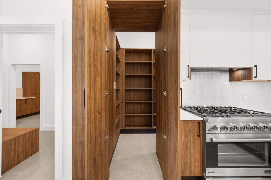 Hidden walk-in pantry seamlessly integrated behind matching custom designed cabinetry.