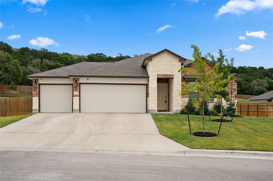View of front of home with a shingled roof, a garage, driveway, stone siding, and brick siding