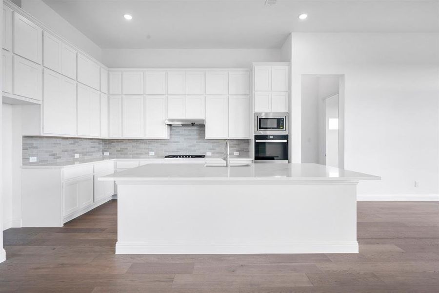 Kitchen featuring a center island with sink, appliances with stainless steel finishes, hardwood / wood-style flooring, and white cabinetry